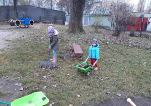 Dzieci porzadkuja ogród z liści.